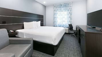 Una habitación de hotel moderna con una cama grande, un escritorio, una silla y un televisor.