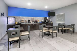 Uma cozinha moderna com parede azul de destaque, área de jantar com seis cadeiras e uma TV de tela plana fixada na parede.