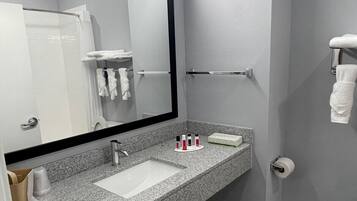 A modern bathroom with a granite countertop, a large mirror, a sink, and a towel rack.