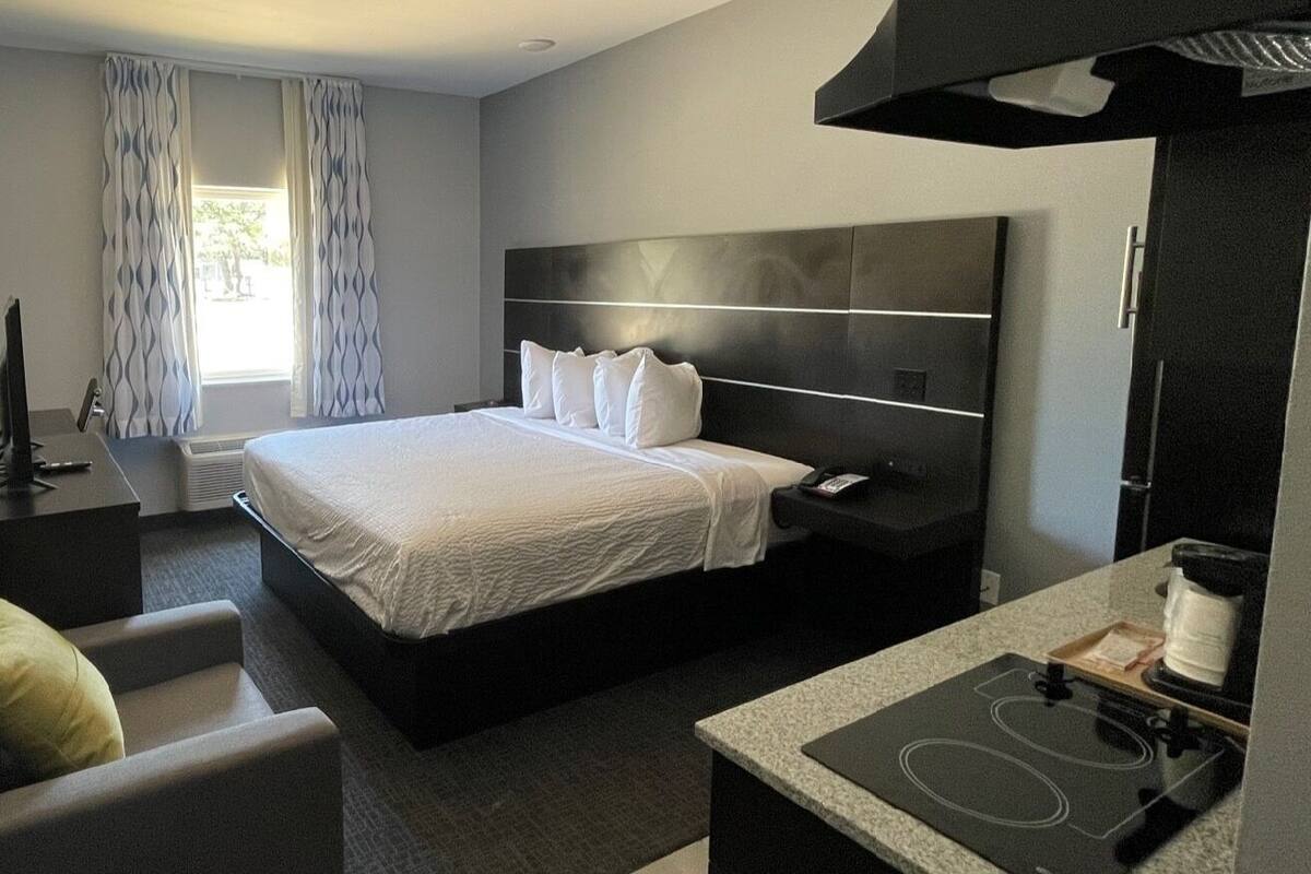 A modern hotel room with a large bed, a desk with a coffee maker, and a TV.
