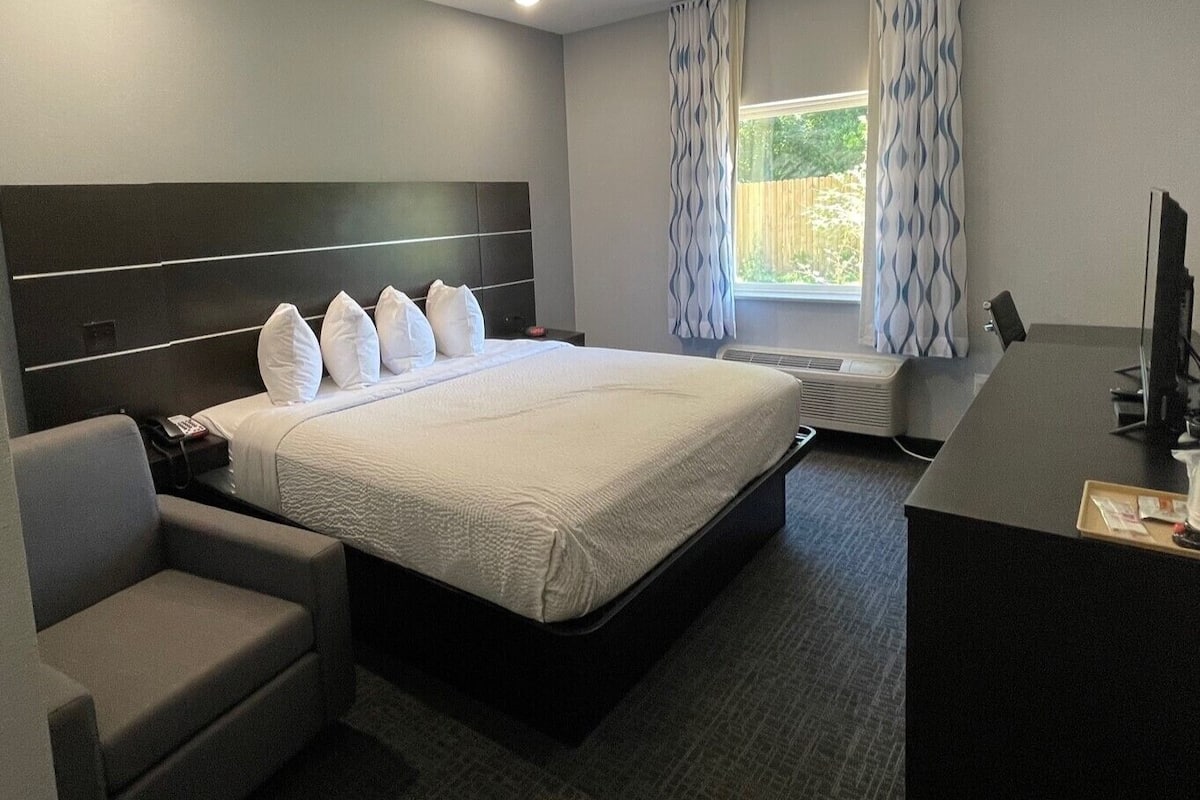 A hotel room with a large bed, a desk, and a chair.