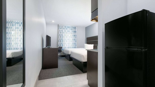Una habitación de hotel con cama, escritorio, televisor de pantalla plana y refrigerador.