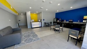 Un moderno vestíbulo de hotel con recepción, área de descanso y kitchenette.