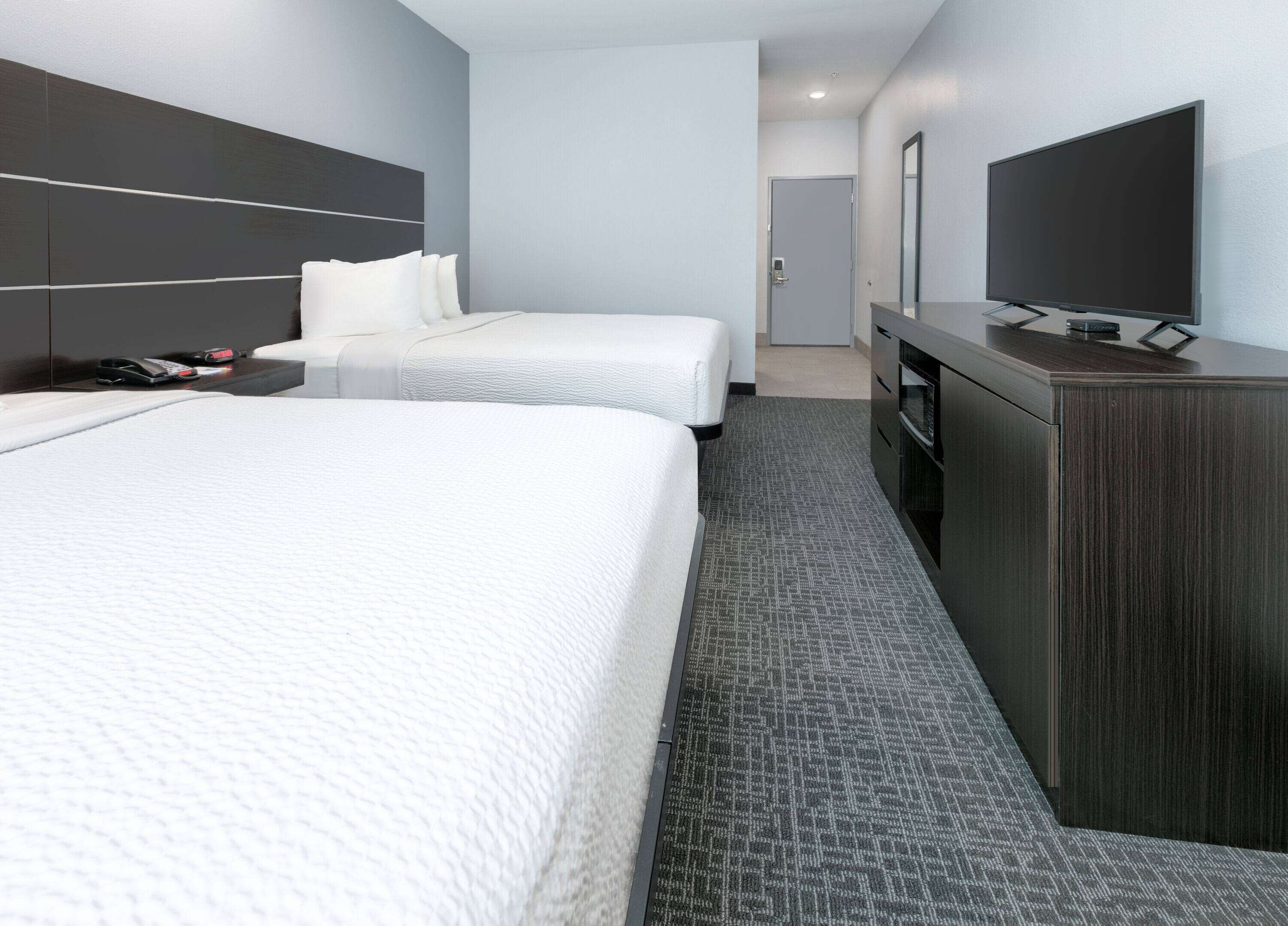 A hotel room with two beds, a TV, a desk, and a wardrobe.