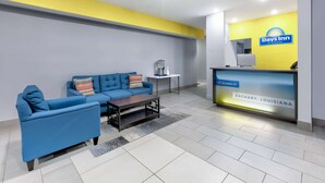 Un área de recepción con un sofá azul, una mesita y un mostrador de recepción con un cartel que dice “Days Inn by Wyndham” en Zachary, Louisiana.