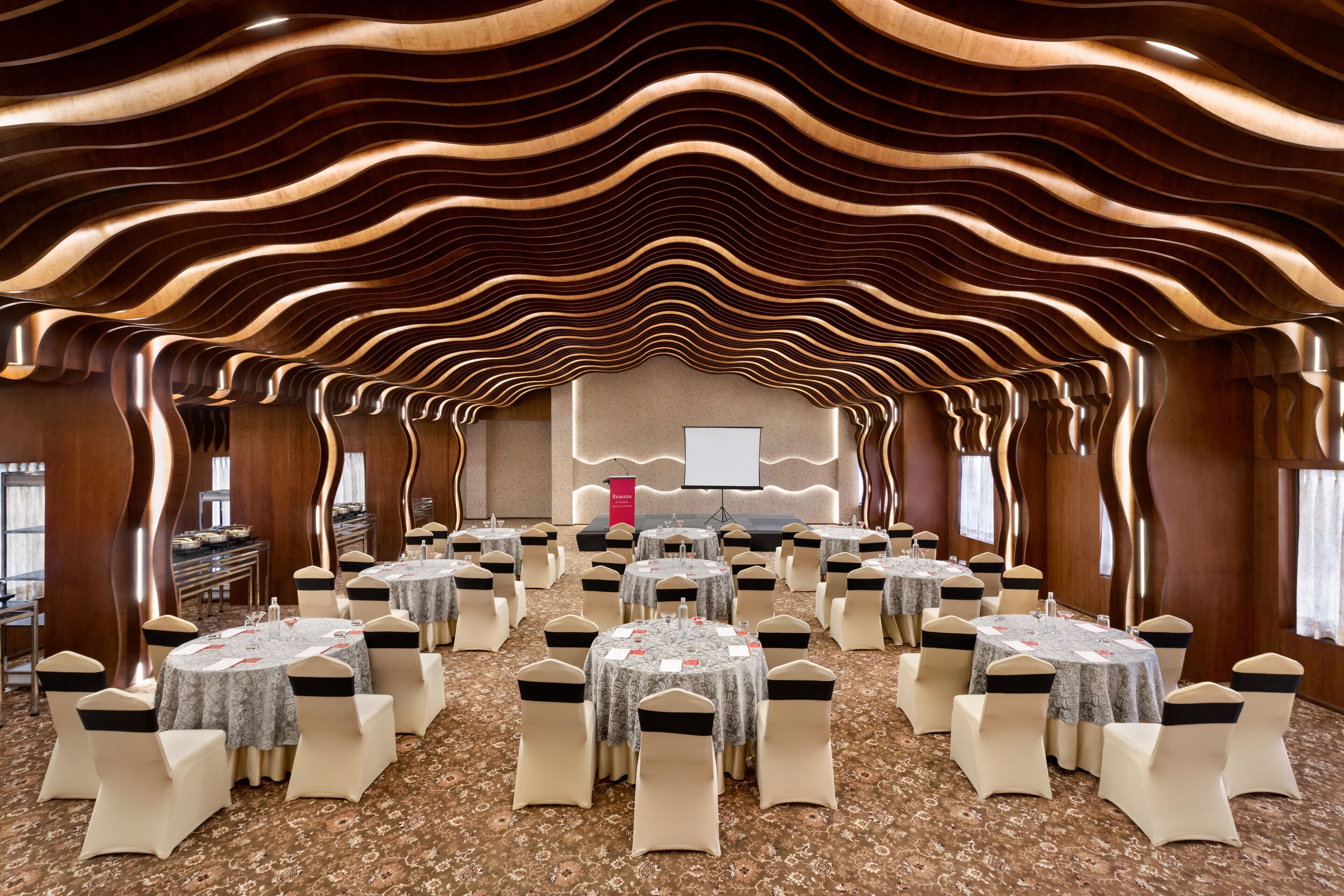 A conference room with round tables, chairs, and a stage.