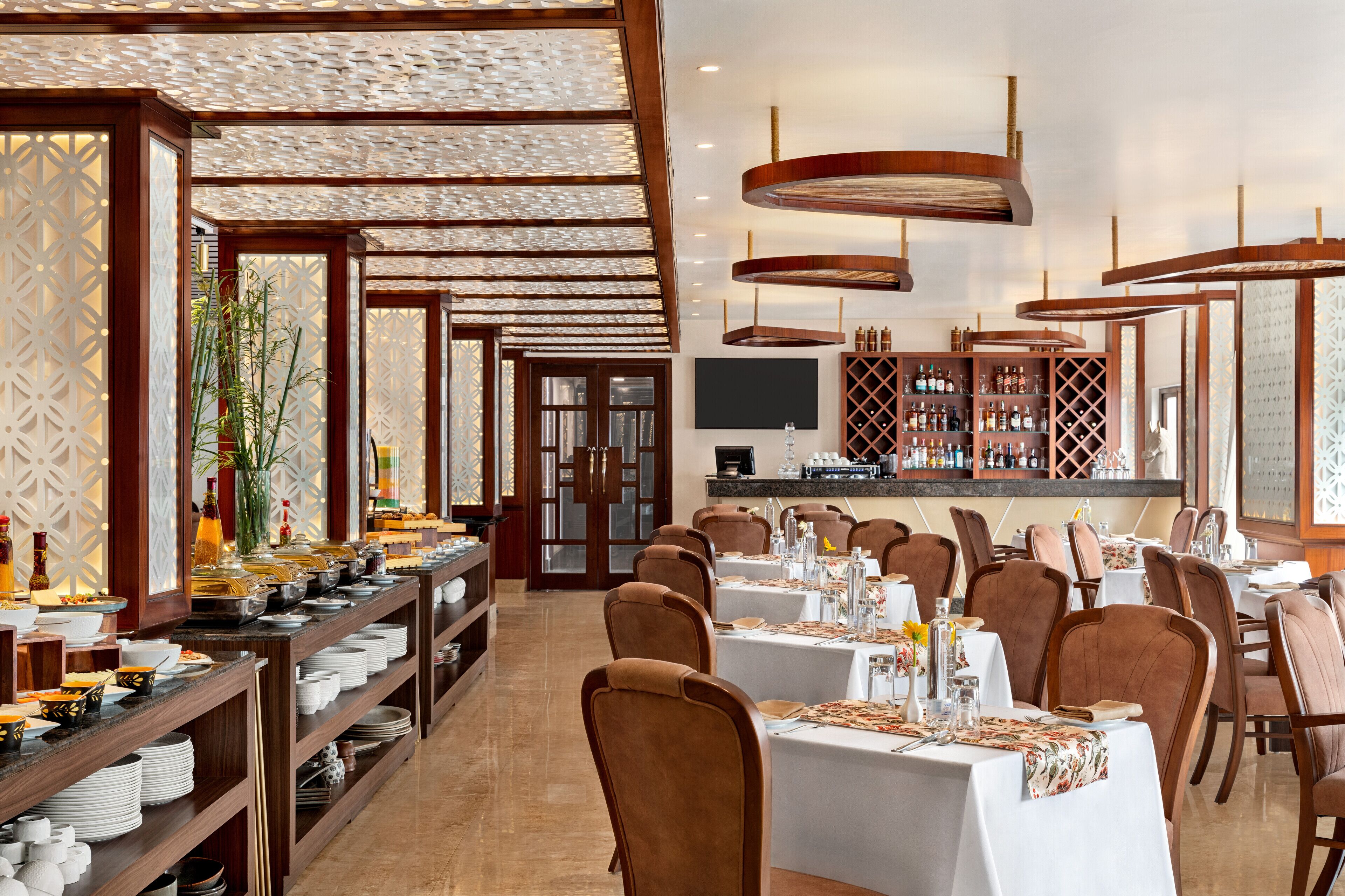 Un restaurant doté de nombreuses tables et chaises, d’un bar et d’un plafond décoratif.
