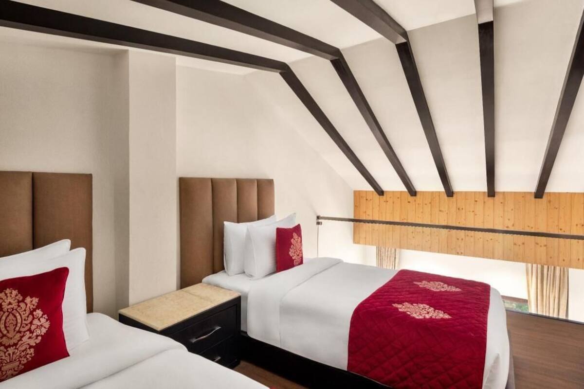 Et moderne hotelværelse med skråvæg, træbjælker og et stort vindue.