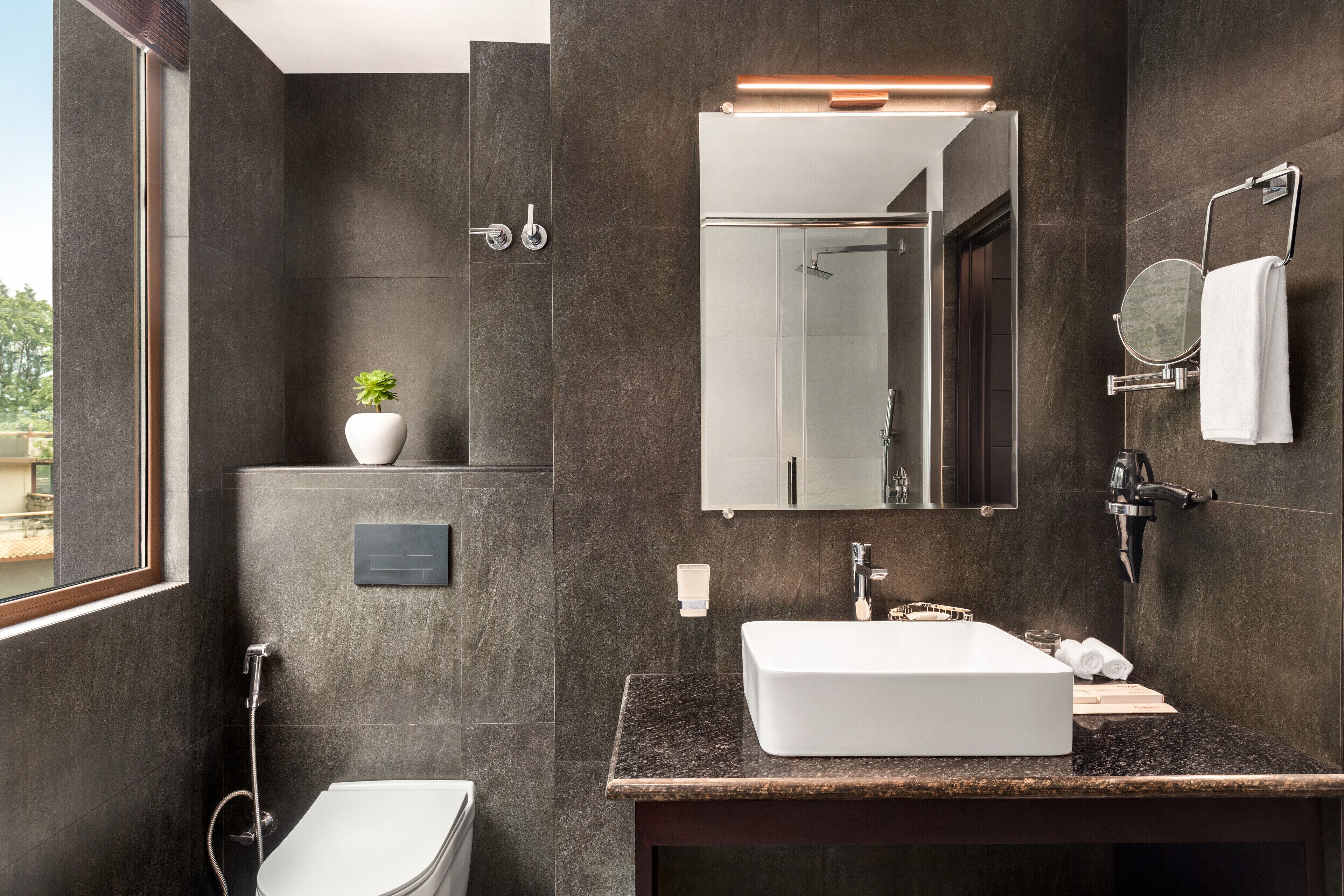 Un bagno moderno con uno specchio grande, un lavandino bianco e una doccia.