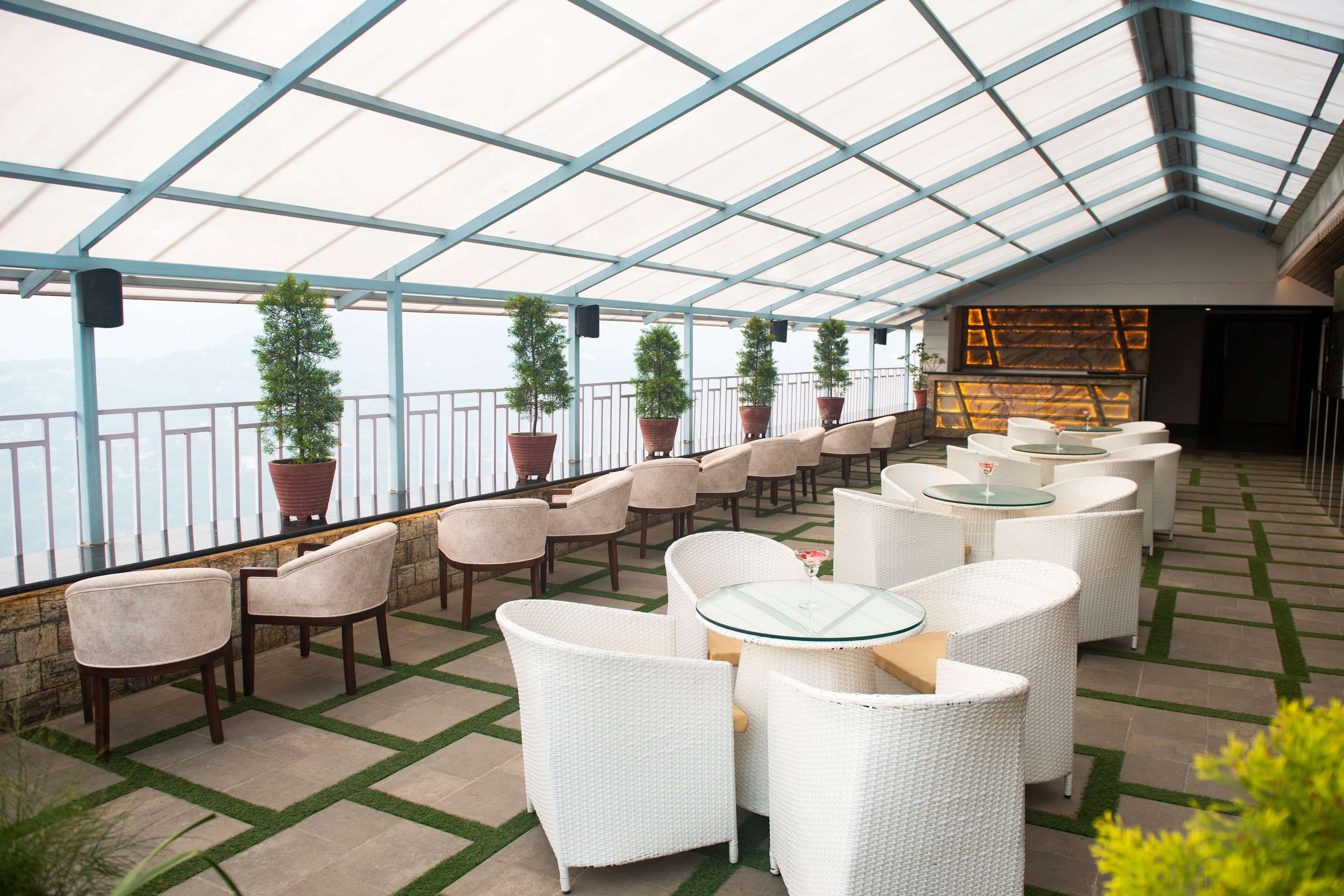 A covered outdoor seating area with white wicker furniture and potted plants.