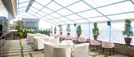 A covered outdoor seating area with wicker furniture and potted plants.