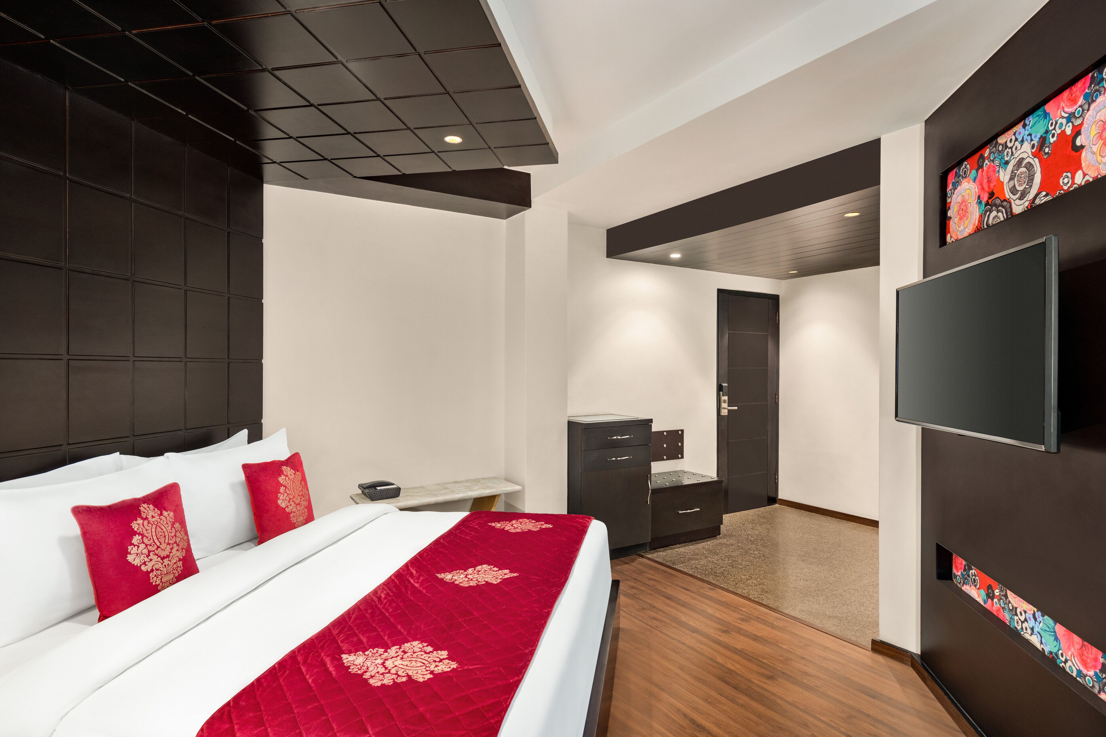 Une chambre d’hôtel moderne, dotée d’un grand lit, d’un bureau, d’une armoire et d’un téléviseur fixé au mur.