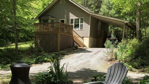 A covered outdoor seating area with Adirondack chairs and a wood-burning stove.