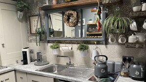 Une cuisine équipée d’un évier, d’un lave-vaisselle, d’une bouilloire et de divers appareils de cuisine.