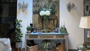 Un salon agrémenté d’un lustre, d’un grand tableau et d’une console sur laquelle sont disposés des objets décoratifs.