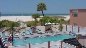 Área da piscina com espreguiçadeiras e vista para a praia.