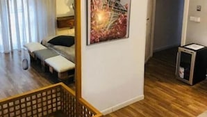 Une chambre d’hôtel avec un plancher en bois, un lit avec un oreiller, une table de chevet, un miroir et une image de la Tour Eiffel.