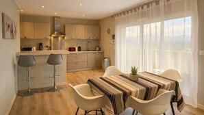 A modern kitchen with a dining area, a view of the city, and a balcony. - Superb ground‑floor villa, 70 m², terrace with sea view & private pool (Grosseto-Prugna)