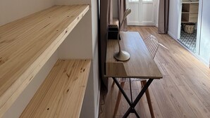 Ein schlicht eingerichteter Raum mit Holzböden, einem Esstisch und Blick durch eine Tür.