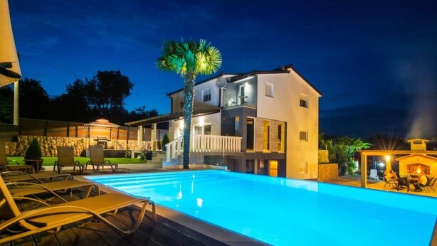 A modern two-story house with a swimming pool, outdoor seating, and a well-lit patio area. - Villa Vida (Zmijavci)