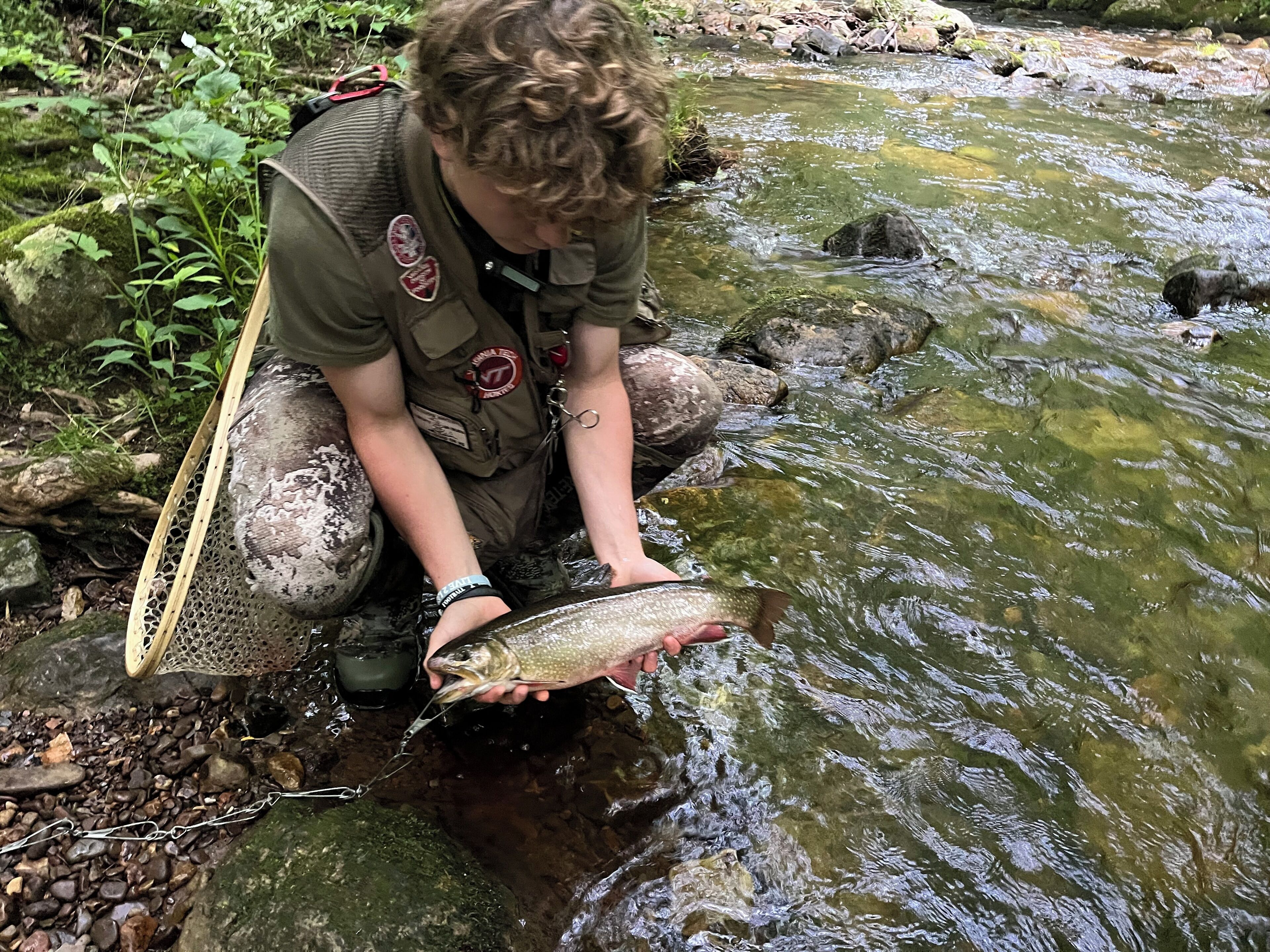 A person holding a fish in a stream.