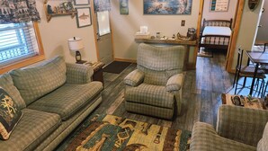 A cozy living room with a sofa, armchair, and a rug with a geometric pattern.