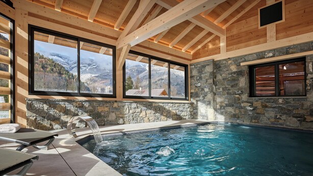 Un intérieur en bois avec un mur en pierre et une piscine.