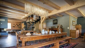 Una habitación amplia con una mesa de madera, bancos y una escalera que lleva a un nivel superior.