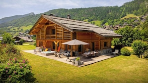 Una cabaña de madera con un patio, mobiliario exterior y un jacuzzi.