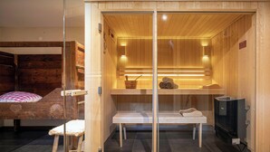 Una sala de sauna con paredes de madera, un banco, una silla y un calentador.