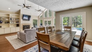 Un salon spacieux avec une grande table à manger en bois, des sièges confortables, une cheminée et un téléviseur.