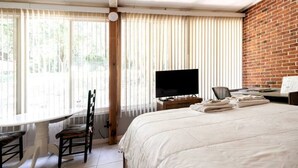 Habitación de hotel con una cama grande, televisor, escritorio y silla.