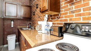 Una cocina con pared de ladrillo, armarios de madera, estufa blanca y encimera de granito.