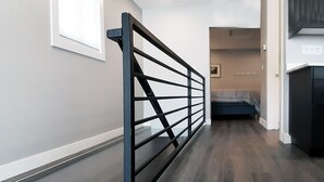 A modern interior with a wooden floor, a black metal railing, and a bed in the background. - Beautifully Designed Space. One Mile to Mayo Clinic. (Rochester)