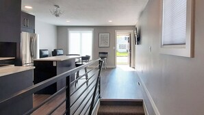 A modern kitchen with a stainless steel refrigerator, a dining area with a counter and chairs, and a staircase leading to a landing. - Beautifully Designed Space. One Mile to Mayo Clinic. (Rochester)