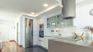 Uma cozinha moderna com eletrodomésticos de aço inoxidável, painel de vidro e piso de madeira.