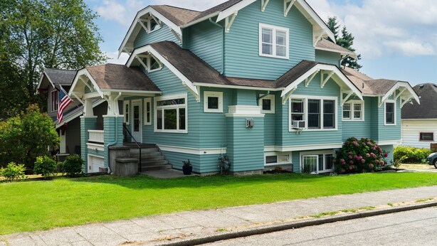 A two-story house with a gabled roof, a front porch, and a well-maintained lawn. - Beautiful Craftsman with Off-street parking, EV charger, Yard + Dogs OK! (Seattle)