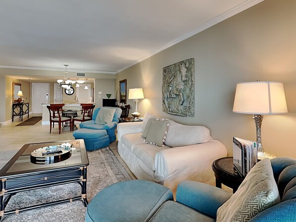 A living room with a sofa, armchairs, a coffee table, and a dining area with a table and chairs. - Breakers East #503 | Stunning Views & Resort Amenities (Destin)