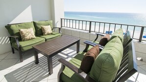 A balcony with a sofa and a table, overlooking a beach. - Destin Beachfront Condo | Stunning Views & Resort Amenities (Destin)