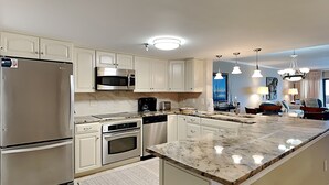 A modern kitchen with stainless steel appliances, white cabinetry, and a marble countertop. - Destin Beachfront Condo | Stunning Views & Resort Amenities (Destin)