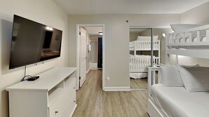 Une chambre dotée d’une télévision, d’un bureau, d’un lit superposé et d’un espace douche.