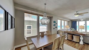 A dining area with a wooden table and chairs, a chandelier, and a ceiling fan.
