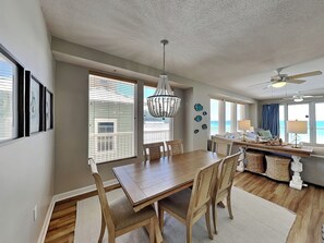 A dining area with a wooden table and chairs, a chandelier, and a ceiling fan.