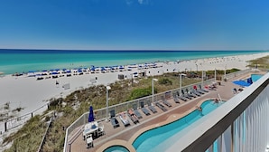 A beach resort with a swimming pool, sun loungers, and umbrellas.