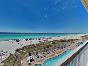 A beach resort with a swimming pool, sun loungers, and umbrellas.