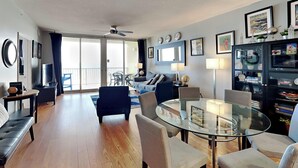 Un salon moderne avec une table à manger en verre, des sièges confortables, un canapé et un balcon avec vue.