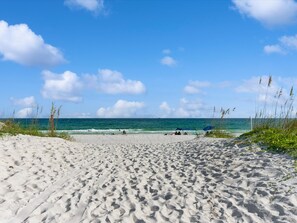 A sandy beach with footprints leading to the water, a clear sky, and the ocean in the background. - Spacious Gulf-front condo w. direct beach access, great pool (Pensacola Beach)