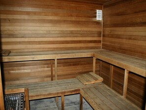 A sauna room with wooden benches and a metal grate.