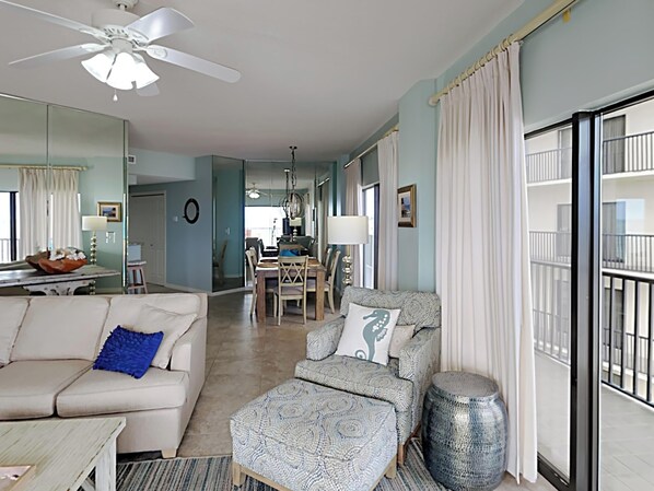 A spacious living room with a sofa, ottoman, and a dining area with chairs and a table.