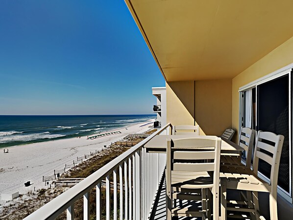 A balcony with a view of the beach and ocean.